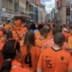 Tientallen mensen in oranje shirts gezien vanaf de rug in een straat in Dortmund